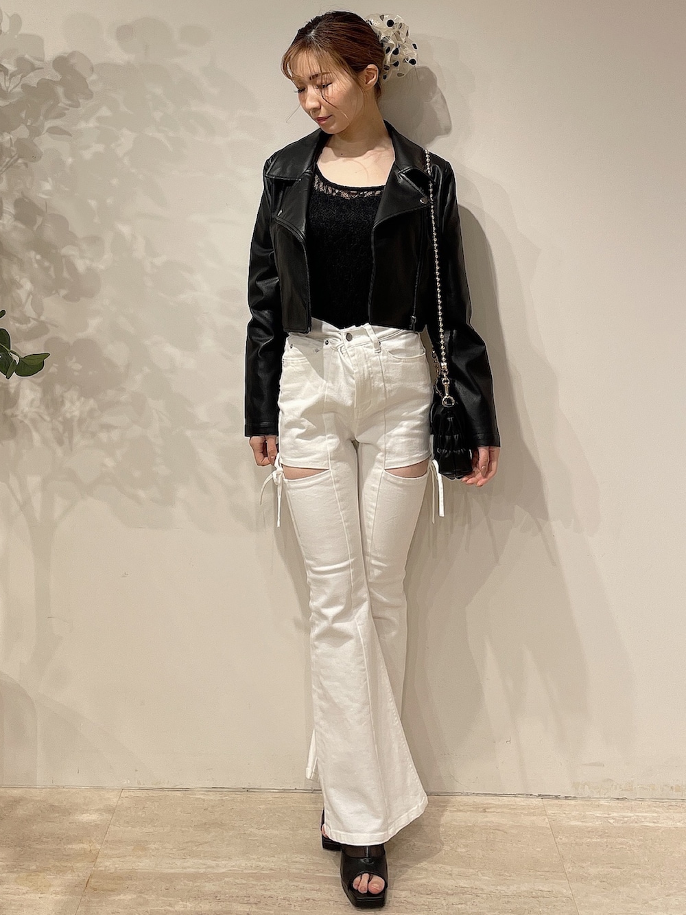 ブラック系のライダースジャケット、ホワイト系のデニムパンツ、ブラック系のブーツを着用したレディースの春コーディネートの2枚目の写真