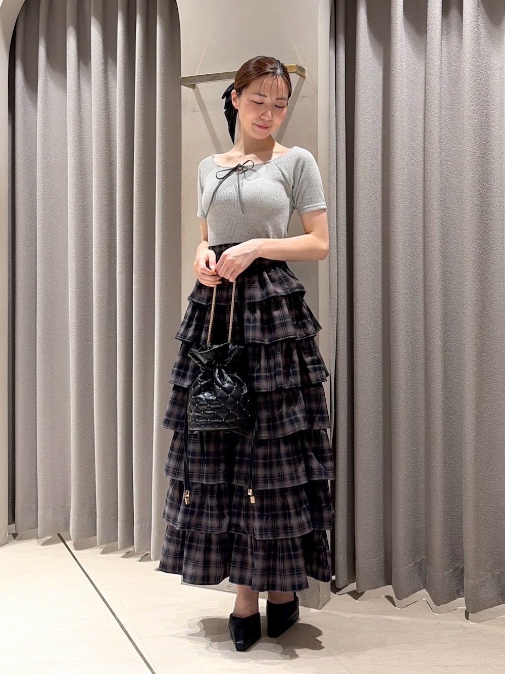 グレー系のTシャツ/カットソー、グレー系のスカート、ブラック系のパンプスを着用したレディースの夏コーディネートの2枚目の写真