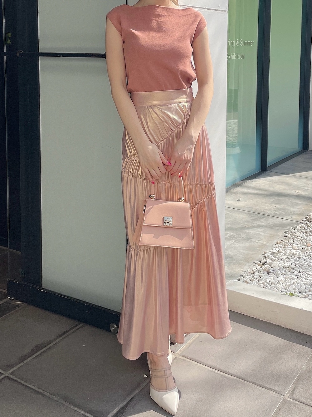 オレンジ系のニット/セーター、ゴールド系のスカート、ピンク系のハンドバッグを着用したレディースの春コーディネートの2枚目の写真