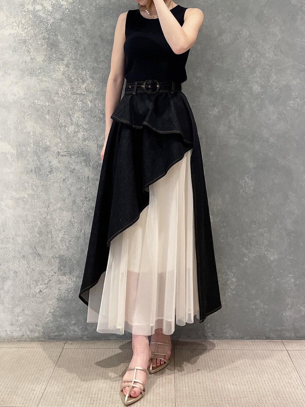 ブラック系のタンクトップ、ブラック系のデニムスカート、ゴールド系のサンダルを着用したレディースの春コーディネートの2枚目の写真