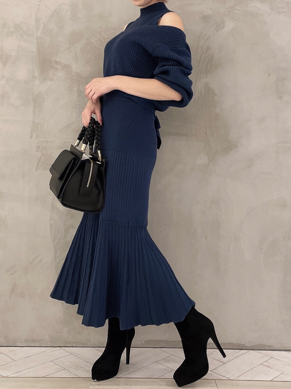 ブルー系のワンピース、ブラック系のブーツ、ブラック系のハンドバッグを着用したレディースの秋コーディネートの2枚目の写真