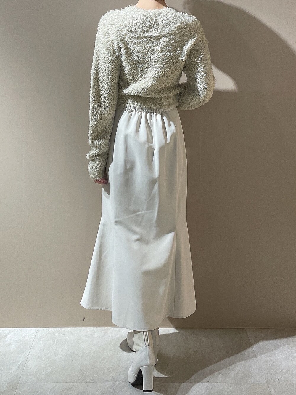 ベージュ系のニット/セーター、ホワイト系のスカート、ホワイト系のブーツを着用したレディースの秋コーディネートの3枚目の写真