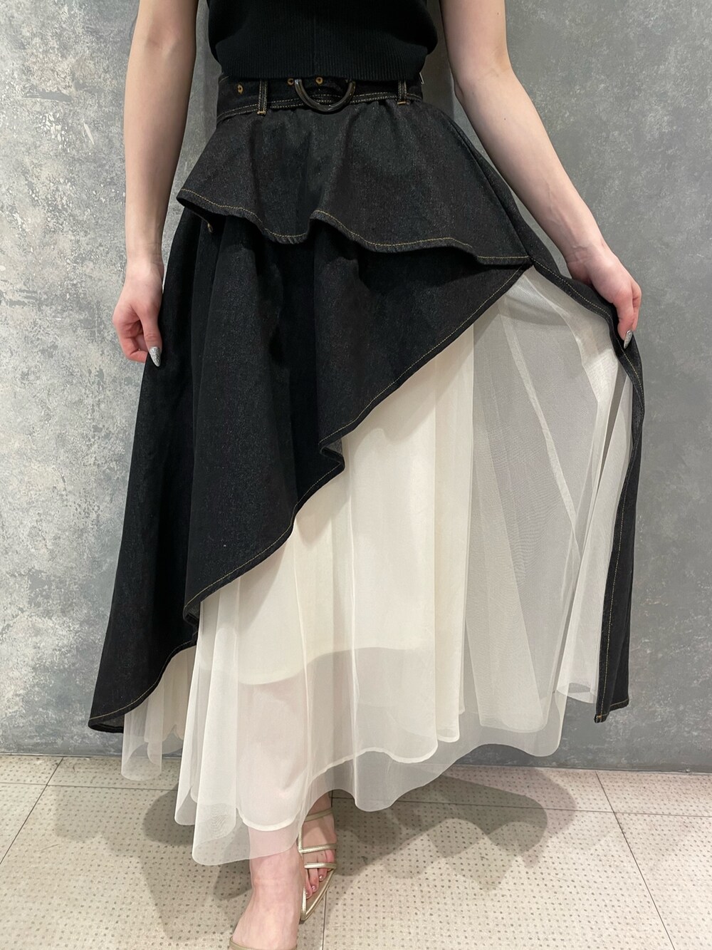 ブラック系のタンクトップ、ブラック系のデニムスカート、ゴールド系のサンダルを着用したレディースの春コーディネートの6枚目の写真