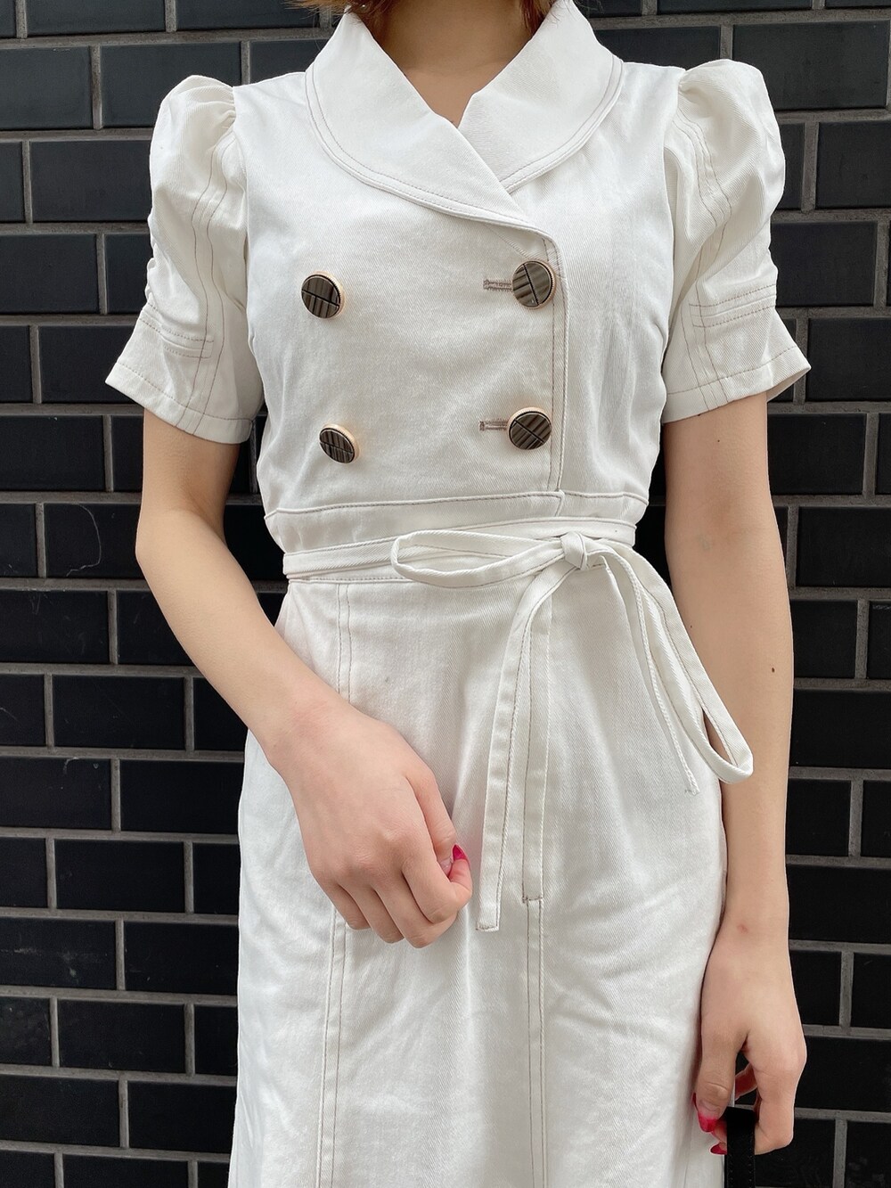 ホワイト系のワンピース、ブラック系のハンドバッグ、ホワイト系のパンプスを着用したレディースの春コーディネートの4枚目の写真