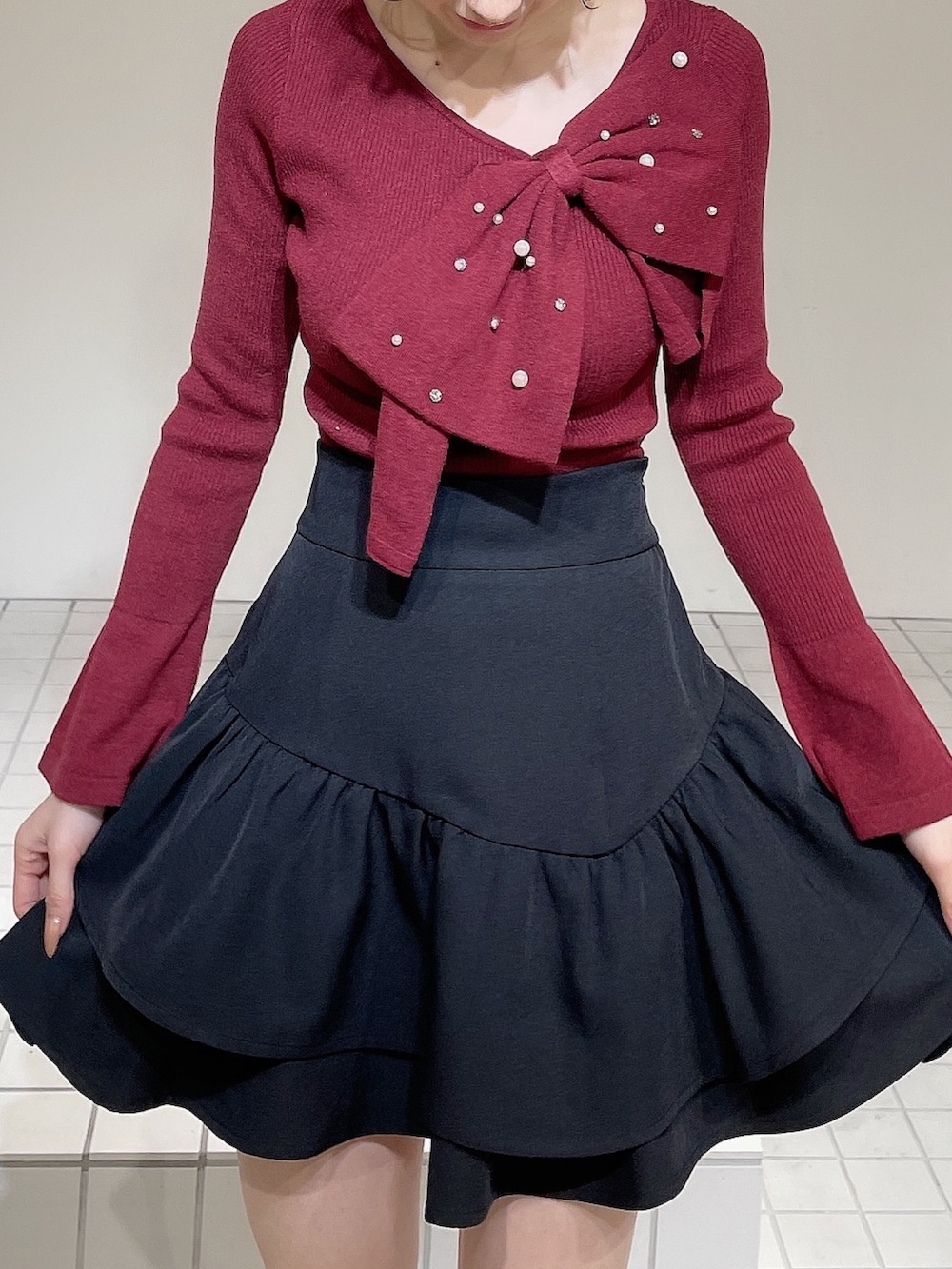 レッド系のニット/セーター、ブラック系のスカート、ブラック系のブーツを着用したレディースの冬コーディネートの5枚目の写真