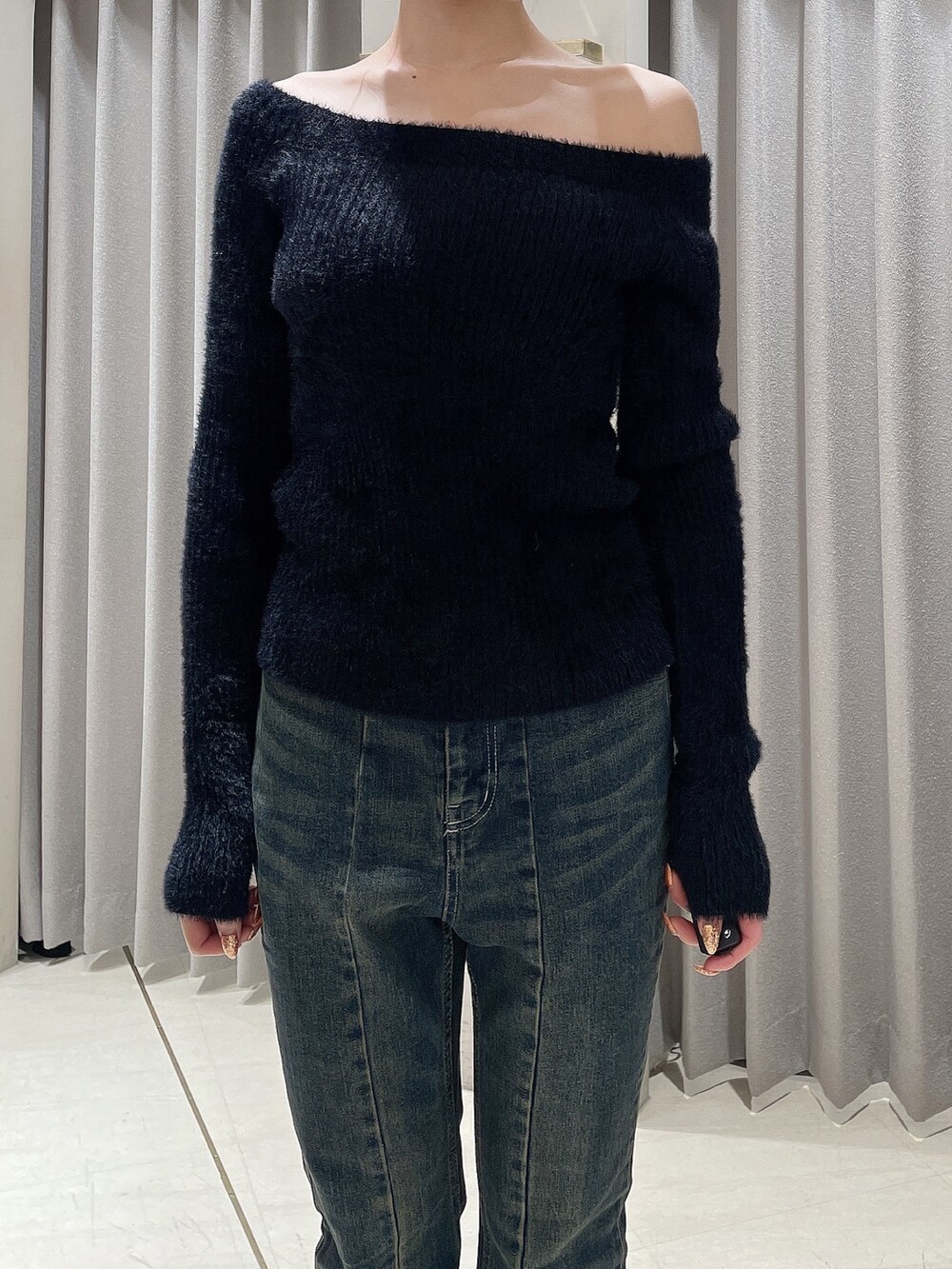 ブルー系のデニムパンツ、ブラック系のニット/セーター、ブラック系のブーツを着用したレディースの秋コーディネートの5枚目の写真