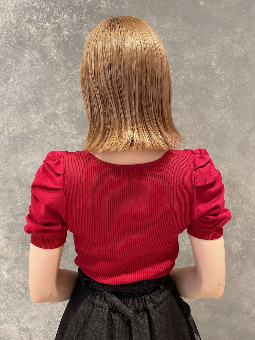 レッド系のニット/セーター、ブラック系のデニムスカート、ブラック系のブーツを着用したレディースの夏コーディネートの6枚目の写真