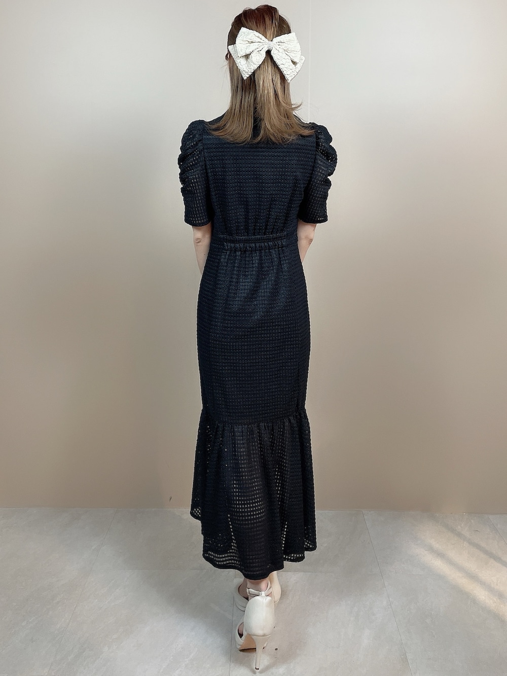 ブラック系のワンピース、ホワイト系のパンプス、ベージュ系のバレッタ/ヘアクリップを着用したレディースの冬コーディネートの3枚目の写真