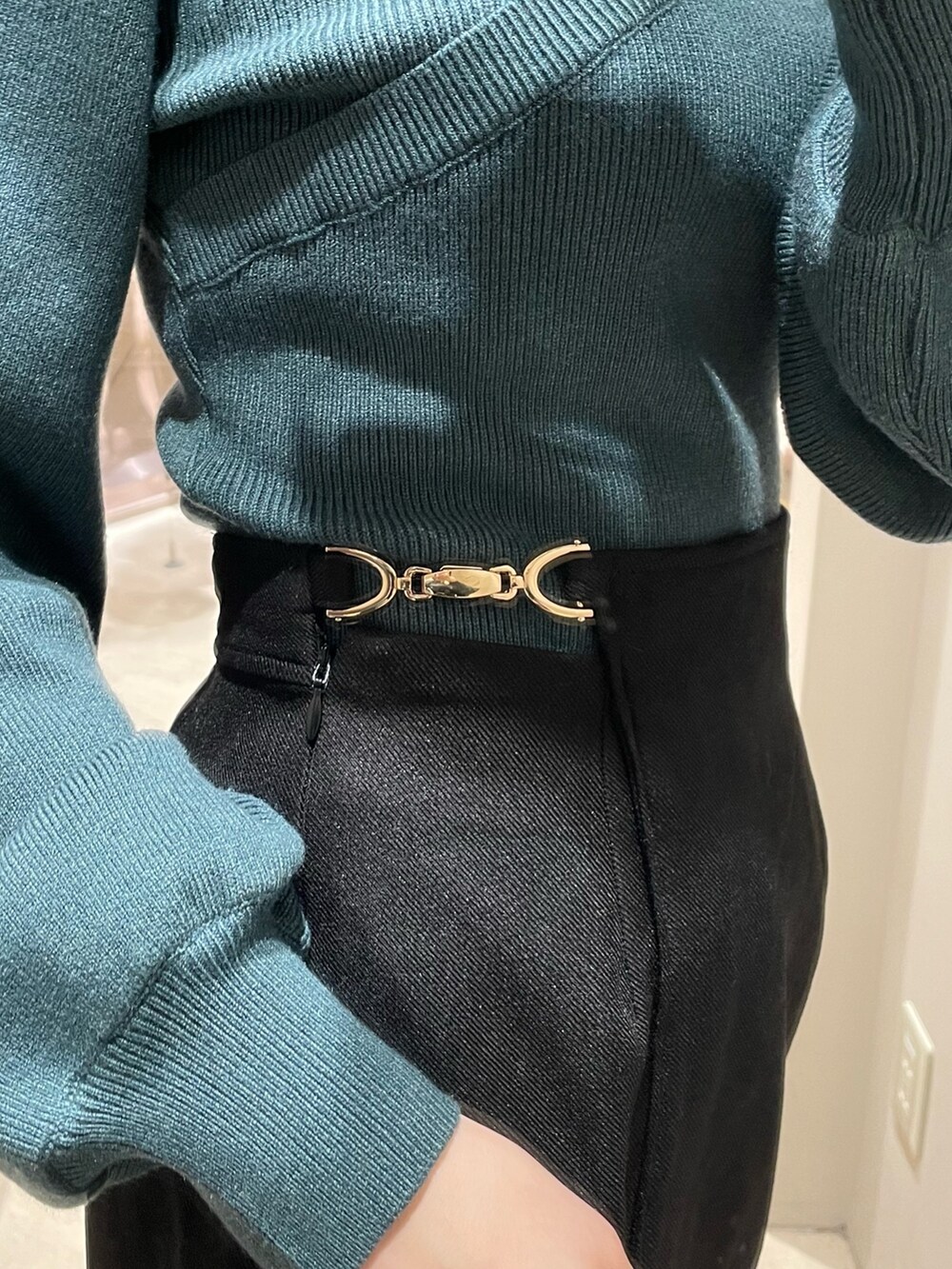 グリーン系のニット/セーター、ブラック系のスカート、ブラック系のブーツを着用したレディースの冬コーディネートの6枚目の写真