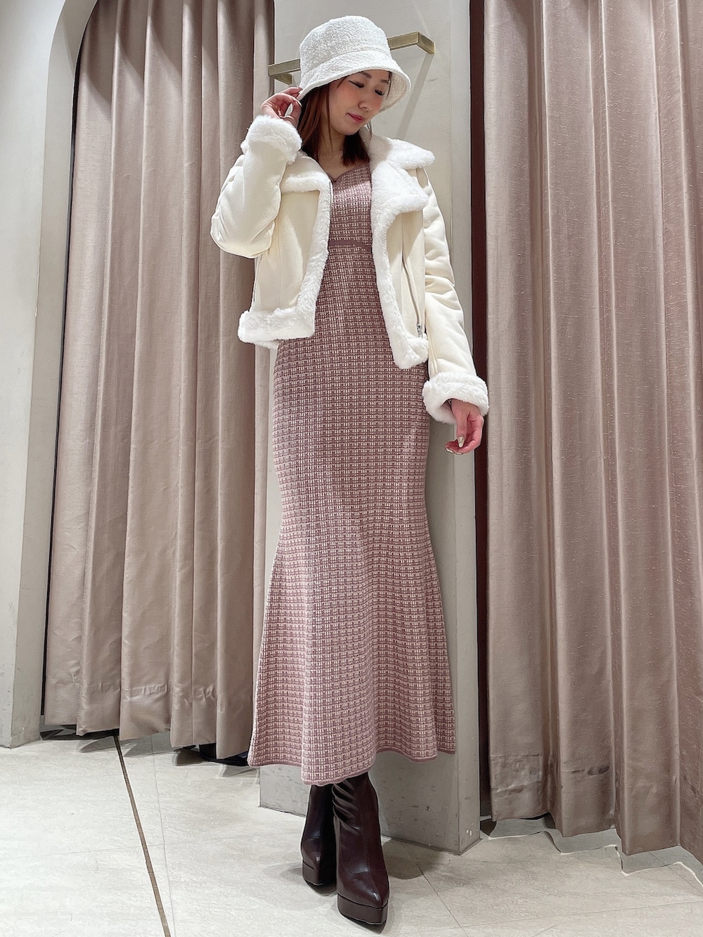 ピンク系のワンピース、ブラウン系のブーツ、ホワイト系のハットを着用したレディースの冬コーディネートの4枚目の写真