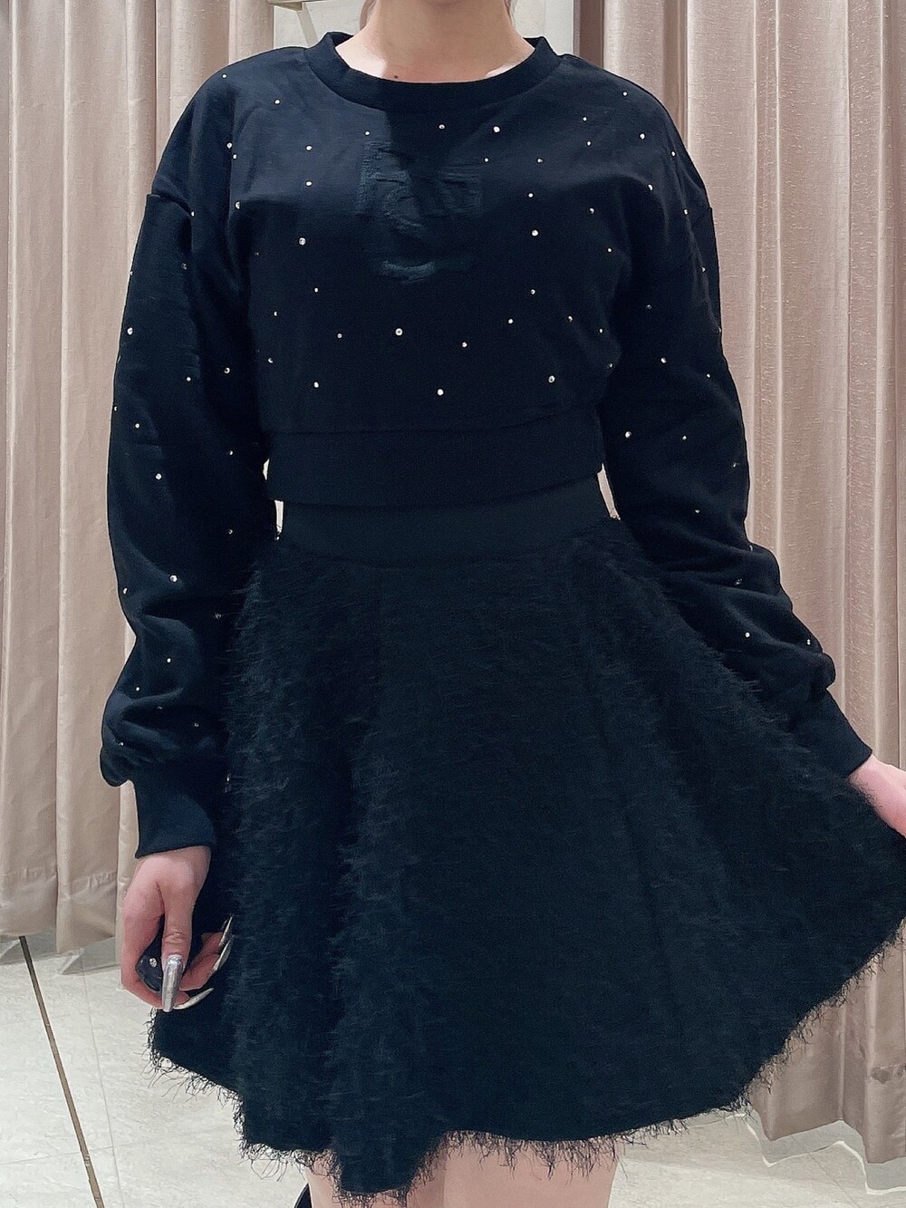 ブラック系のスウェット、ブラック系のスカート、ブラック系のブーツを着用したレディースの秋コーディネートの5枚目の写真