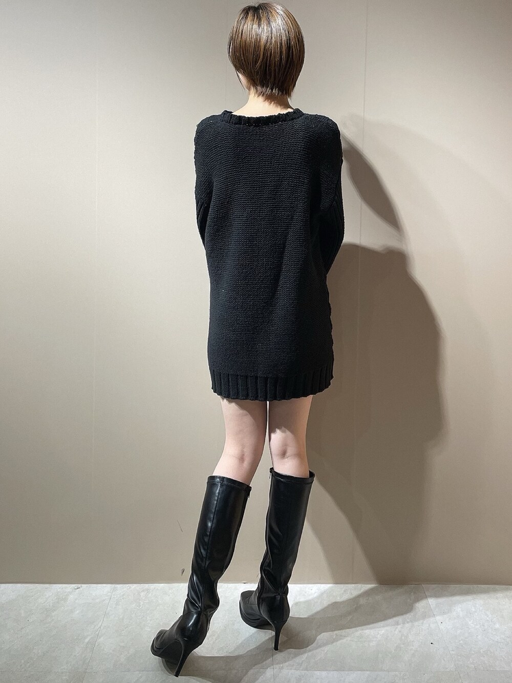 ブラック系のニット/セーター、グレー系のチェスターコート、ブラック系のブーツを着用したレディースの秋コーディネートの7枚目の写真