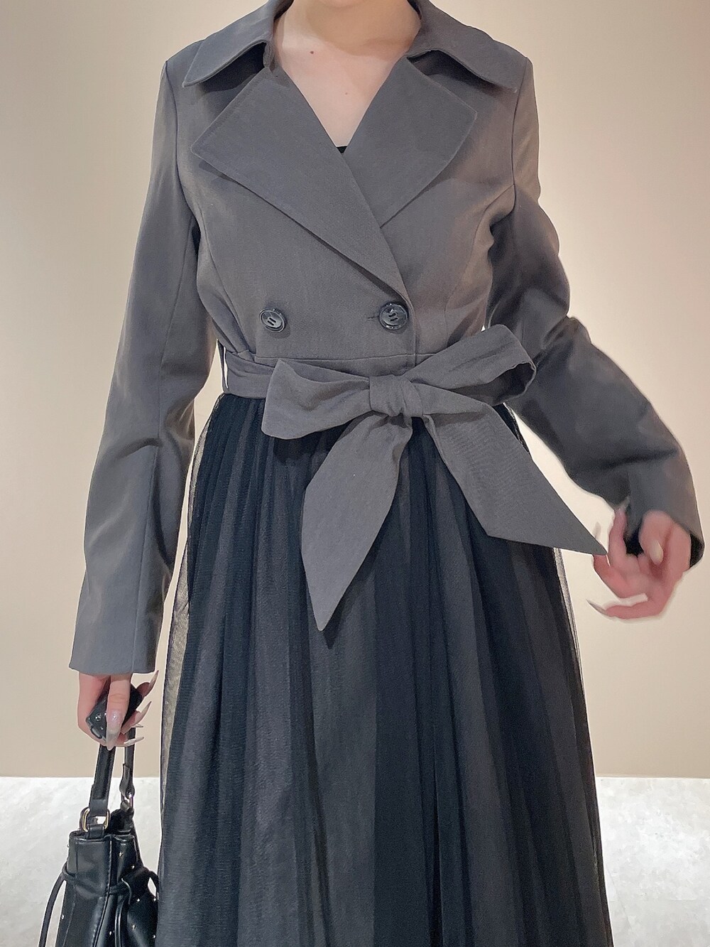 グレー系のトレンチコート、ブラック系のハンドバッグ、ブラック系のブーツを着用したレディースの秋コーディネートの7枚目の写真