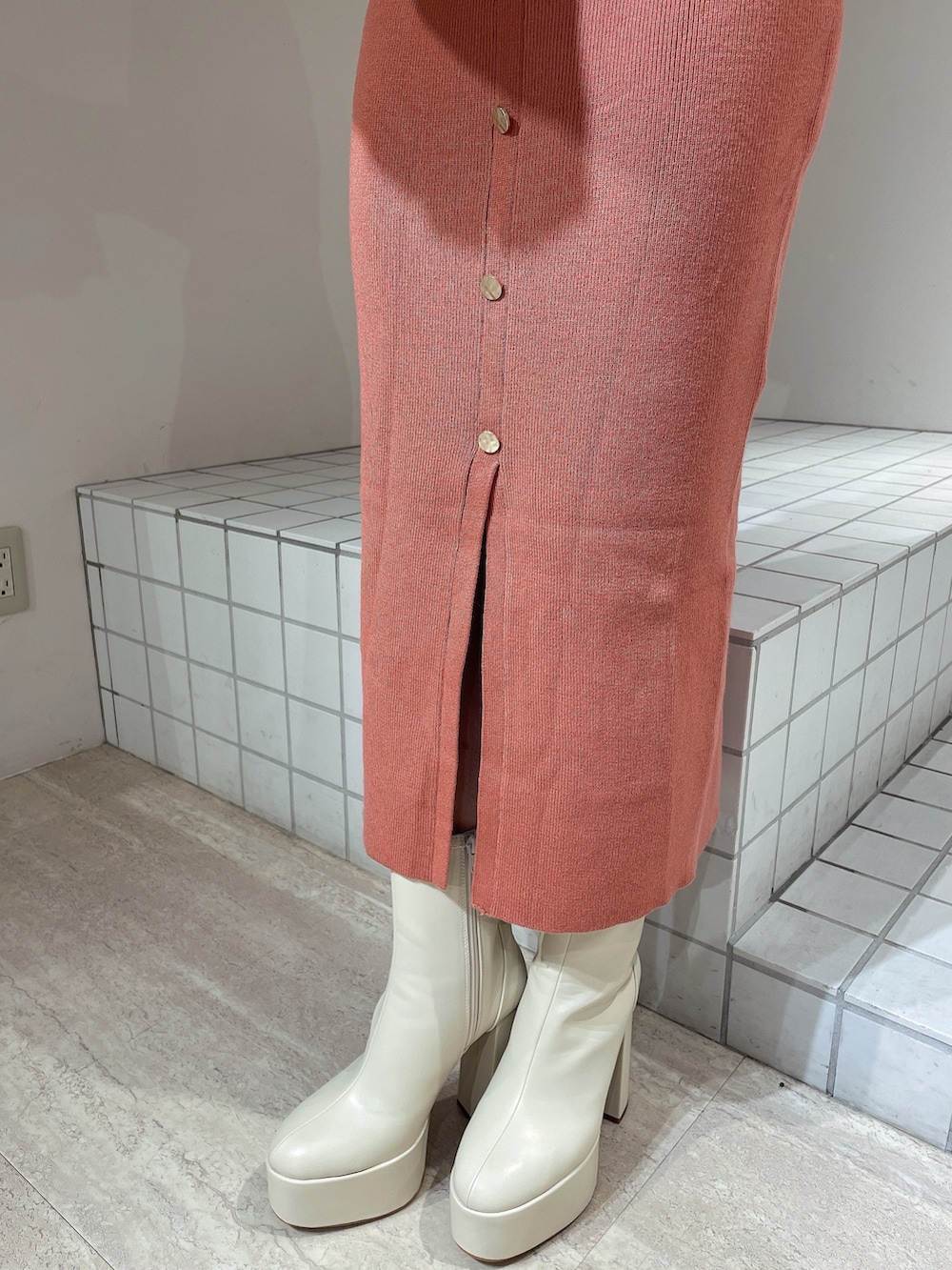 オレンジ系のワンピース、ホワイト系のハンドバッグ、ホワイト系のブーツを着用したレディースの冬コーディネートの5枚目の写真