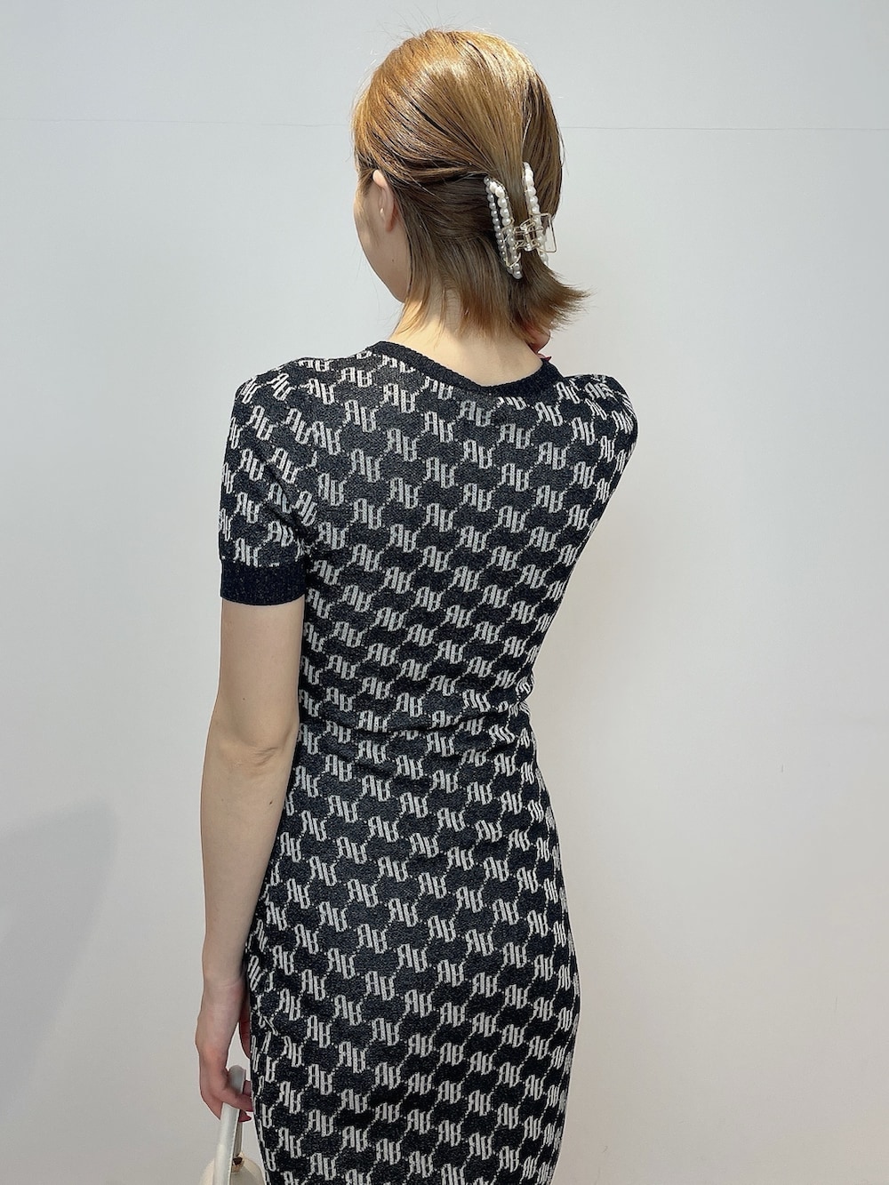 ホワイト系のハンドバッグ、ホワイト系のサンダル、ブラック系のワンピースを着用したレディースの春コーディネートの6枚目の写真