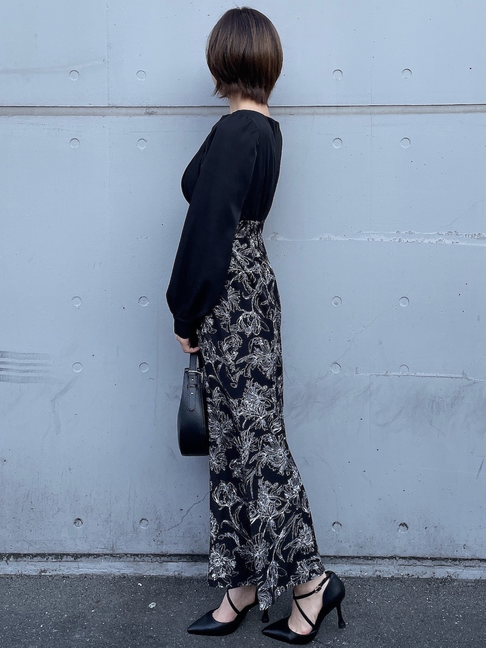 ベージュ系のトレンチコート、ブラック系のワンピース、ブラック系のハンドバッグを着用したレディースの冬コーディネートの2枚目の写真