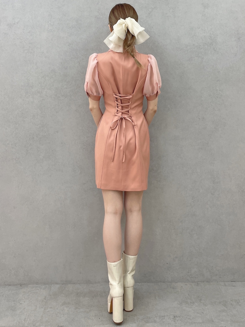 オレンジ系のワンピース、ホワイト系のブーツ、ホワイト系のバレッタ/ヘアクリップを着用したレディースの春コーディネートの4枚目の写真