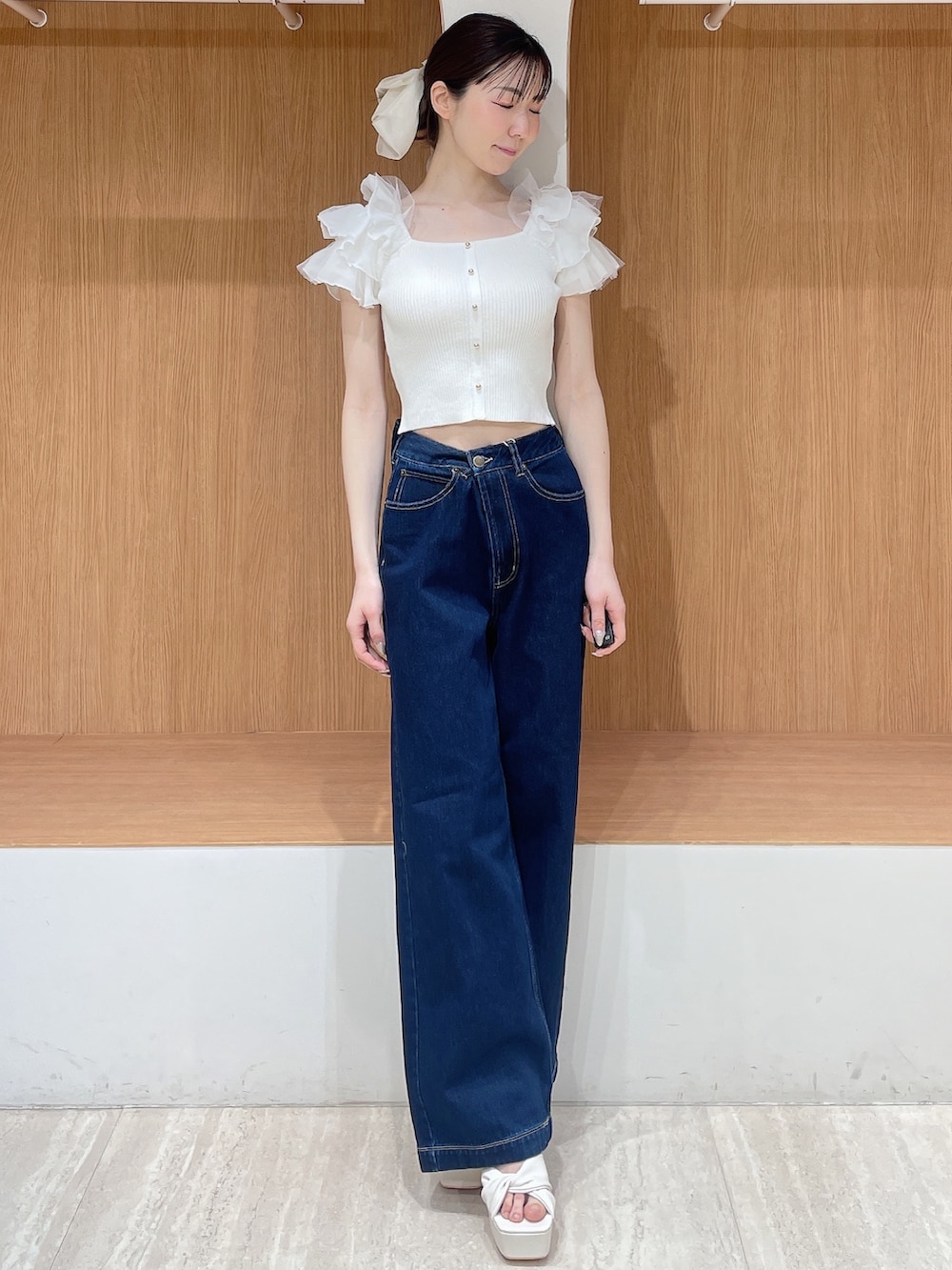 ホワイト系のニット/セーター、ブルー系のデニムパンツ、ホワイト系のサンダルを着用したレディースの春コーディネートの2枚目の写真