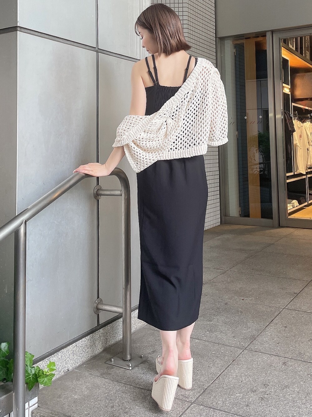 ホワイト系のカーディガン/ボレロ、ブラック系のワンピース、ホワイト系のサンダルを着用したレディースの夏コーディネートの6枚目の写真