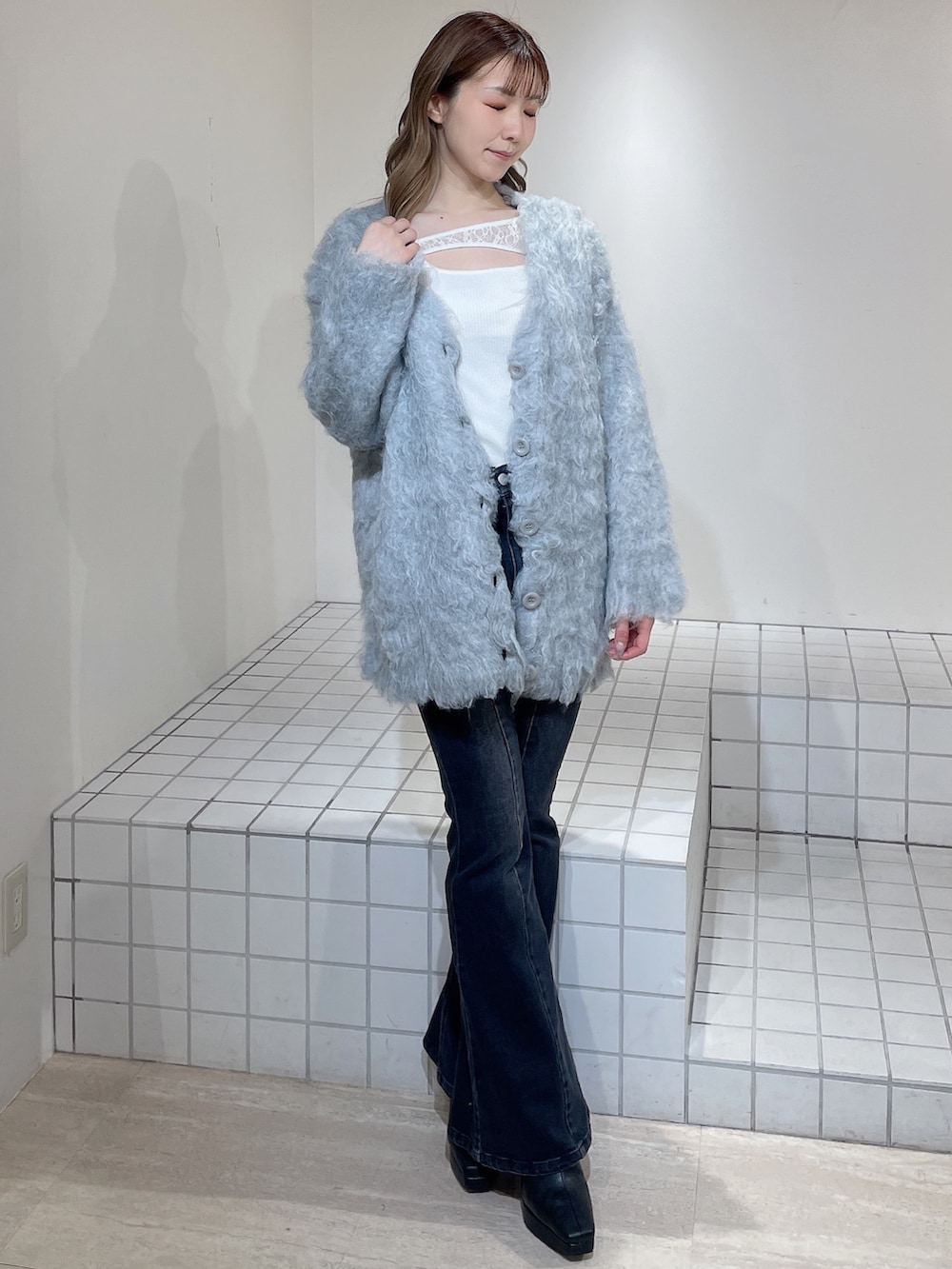 グレー系のカーディガン/ボレロ、ホワイト系のニット/セーター、ブラック系のデニムパンツを着用したレディースの冬コーディネートの2枚目の写真