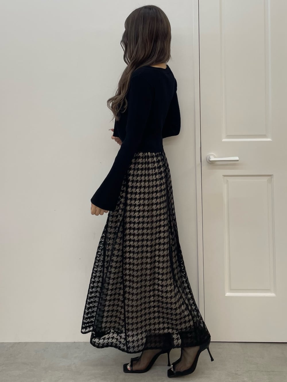 ブラック系のニット/セーター、ブラック系のスカート、ブラック系のブーツを着用したレディースの秋コーディネートの3枚目の写真