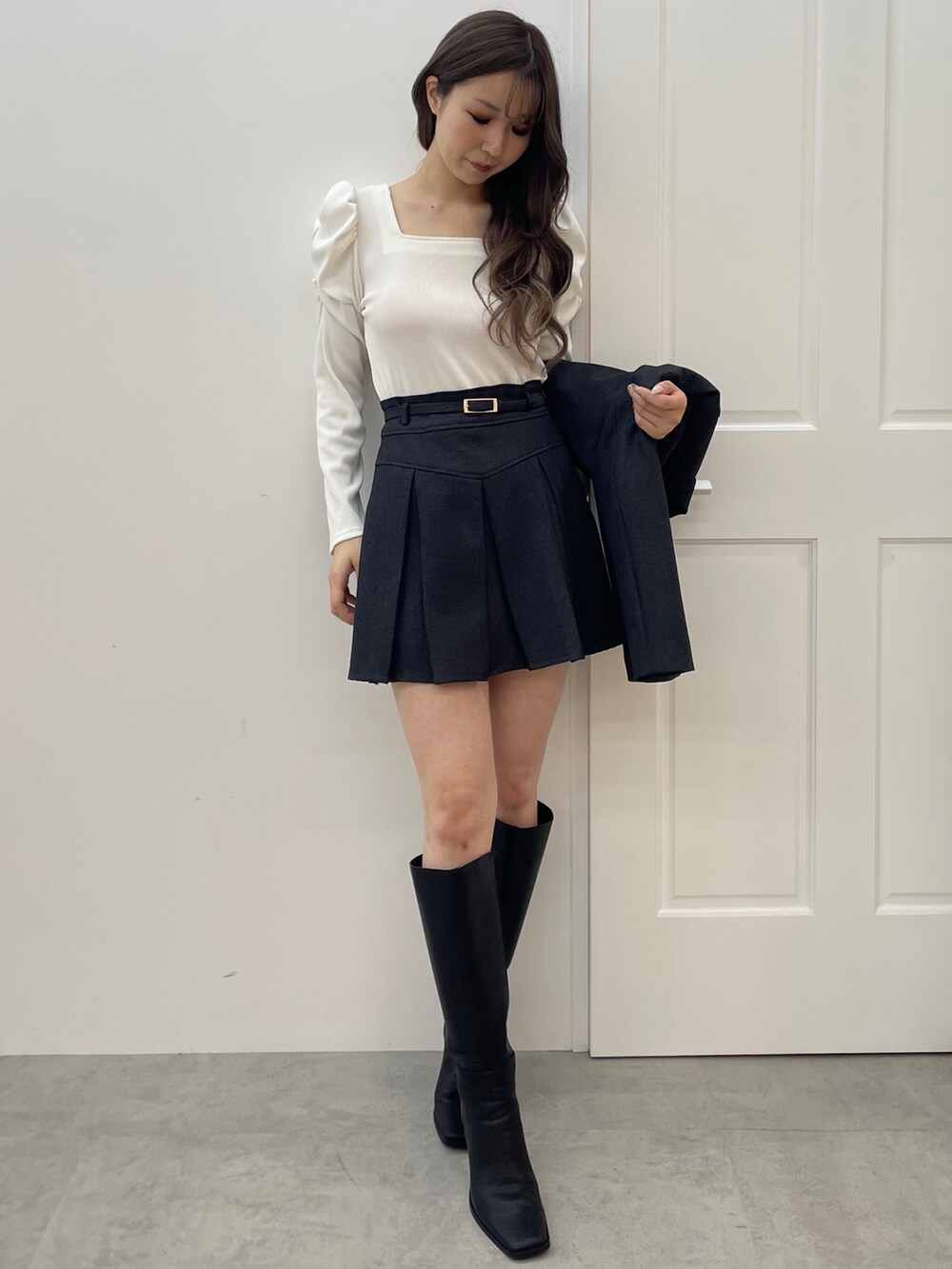 グレー系のテーラードジャケット、グレー系のスカート、ブラック系のブーツを着用したレディースの夏コーディネートの5枚目の写真