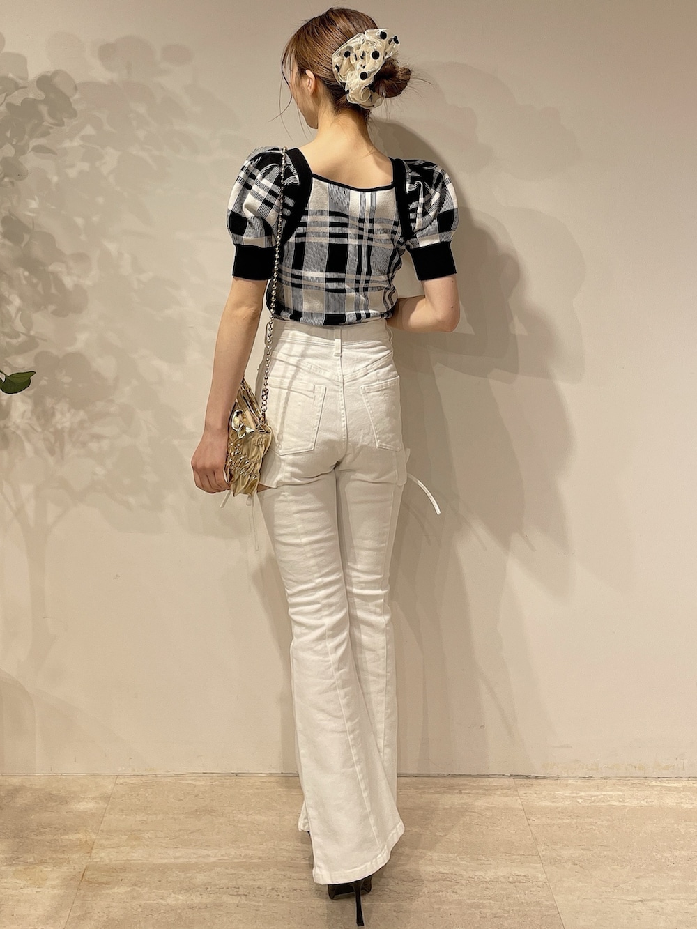 ブラック系のニット/セーター、ホワイト系のデニムパンツ、ゴールド系のハンドバッグを着用したレディースの春コーディネートの4枚目の写真