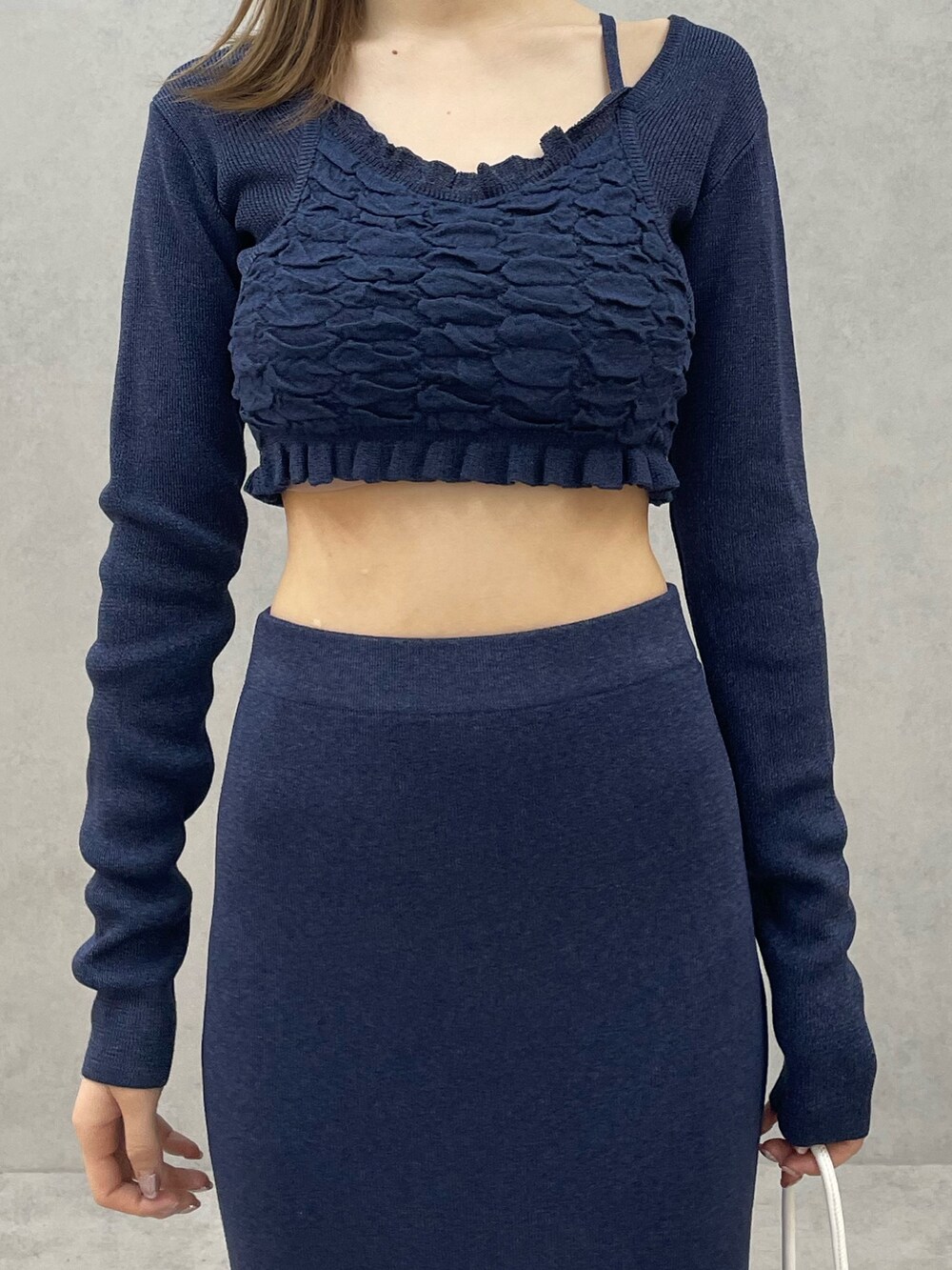 ブルー系のニット/セーター、ブルー系のスカート、ホワイト系のハンドバッグを着用したレディースの春コーディネートの6枚目の写真