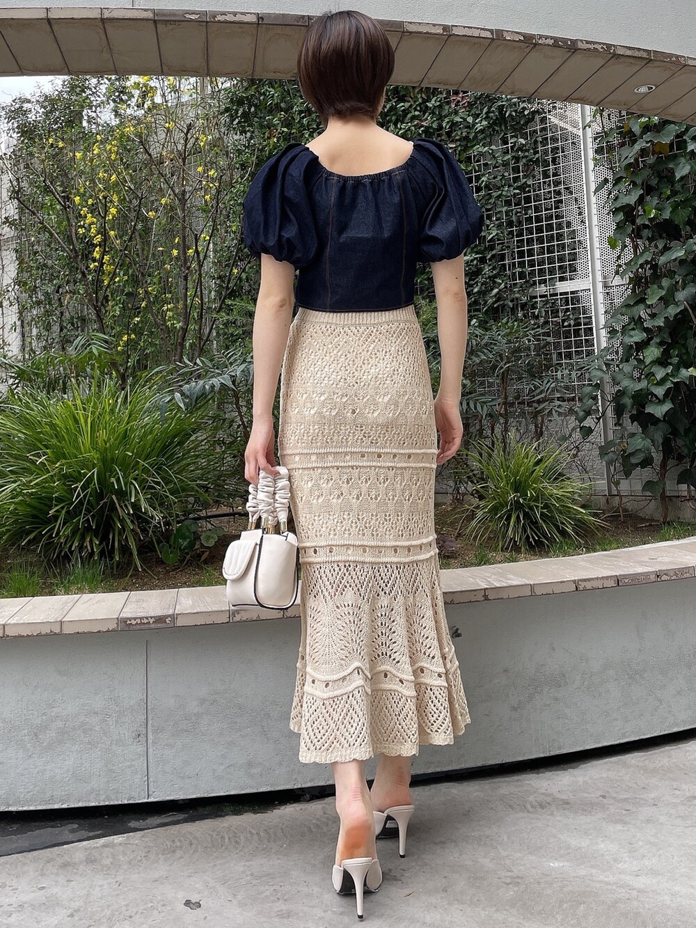 ホワイト系のサンダル、ホワイト系のハンドバッグ、ブルー系のシャツ/ブラウスを着用したレディースの春コーディネートの2枚目の写真