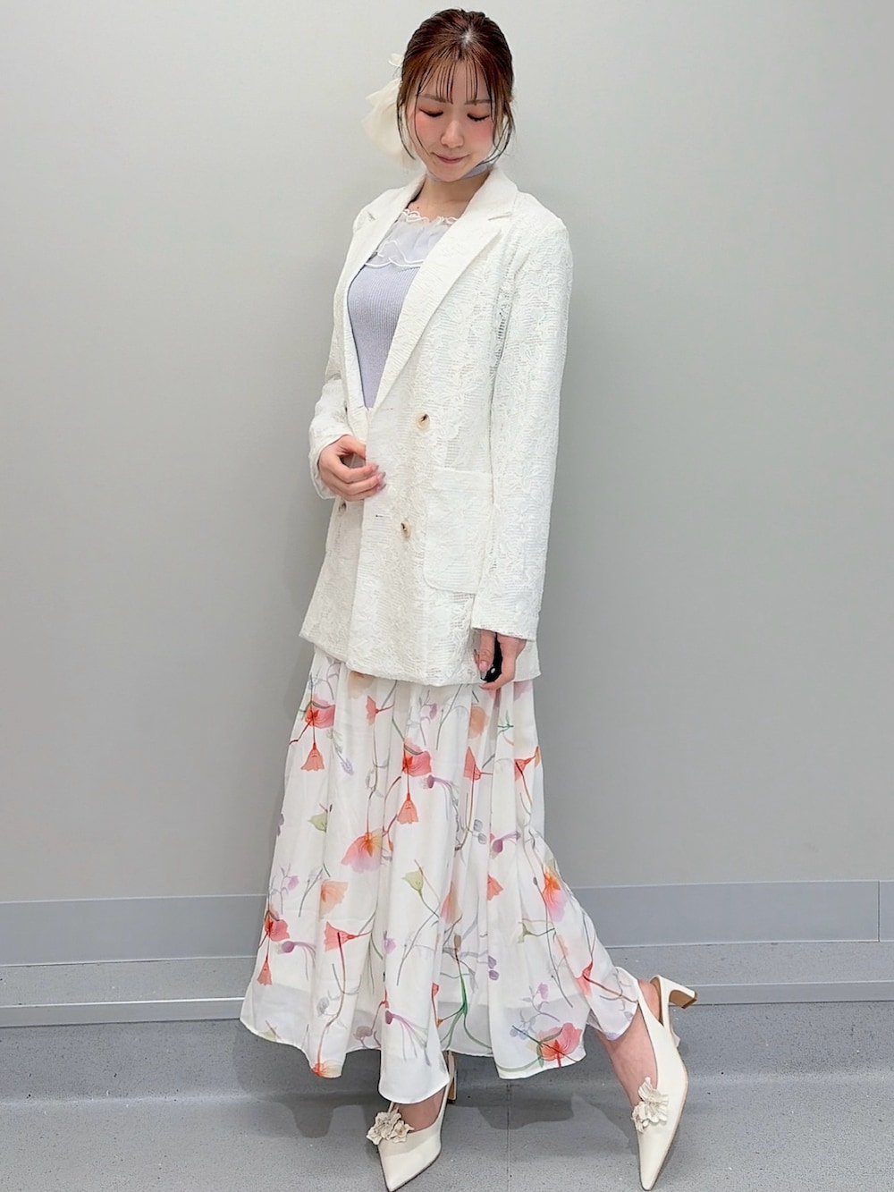 ホワイト系のテーラードジャケット、パープル系のニット/セーター、ホワイト系のスカートを着用したレディースの冬コーディネートの2枚目の写真