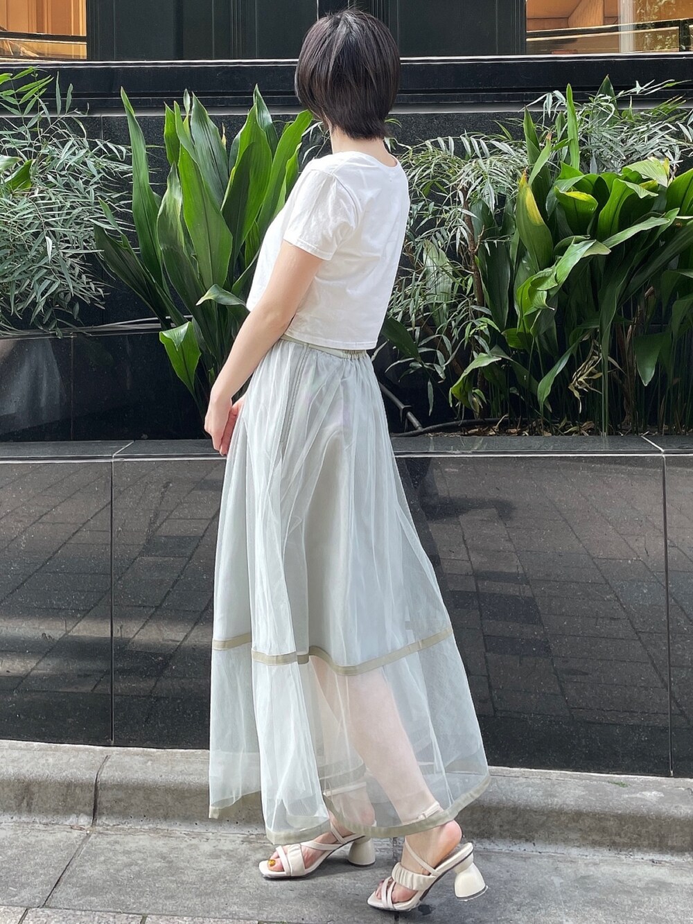 グリーン系のスカート、ホワイト系のサンダル、ホワイト系のTシャツ/カットソーを着用したレディースの春コーディネートの3枚目の写真