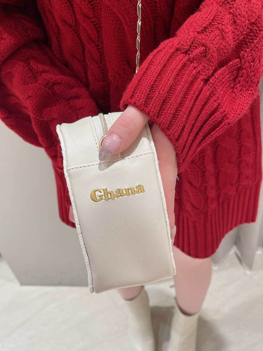 レッド系のニット/セーター、ホワイト系のスカート、ホワイト系のショルダーバッグを着用したレディースの冬コーディネートの9枚目の写真