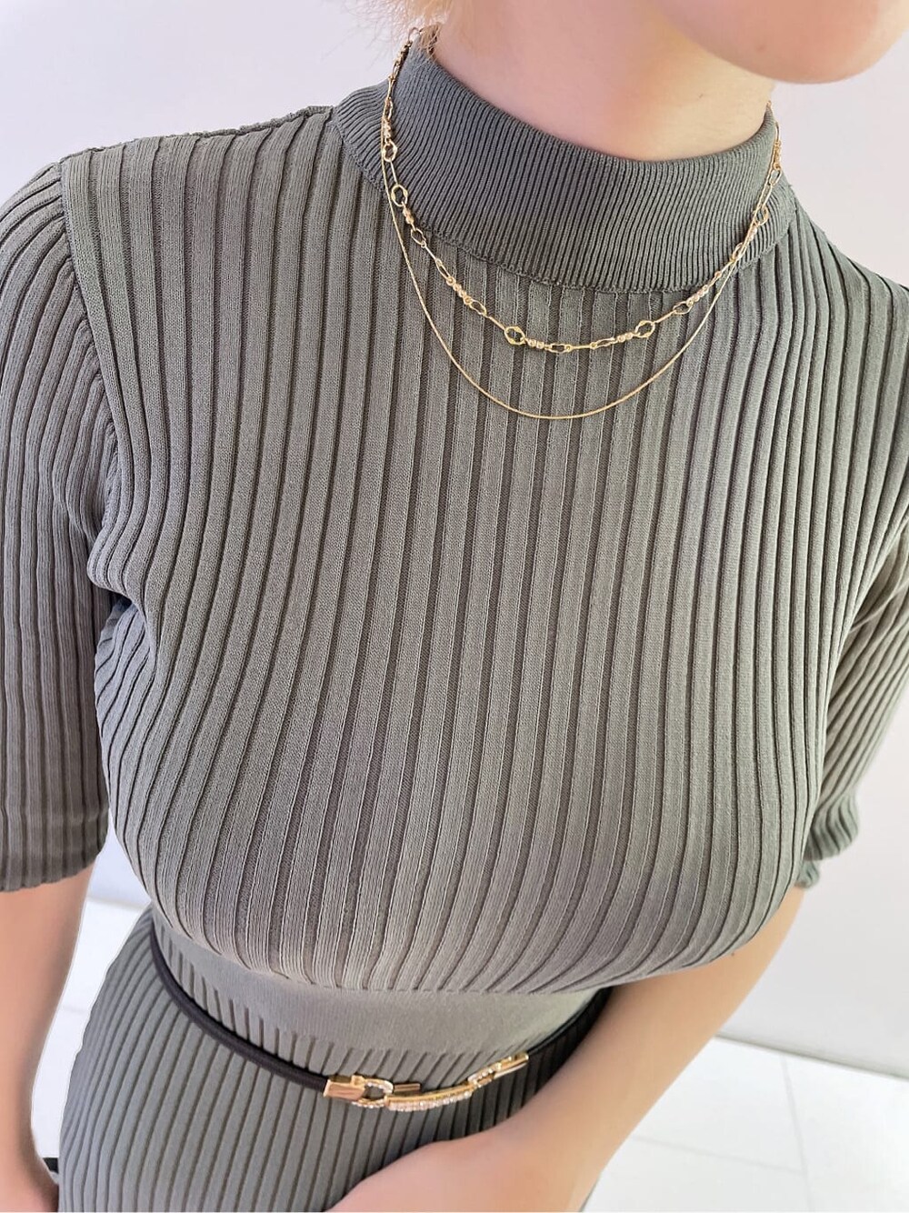 ブラック系のハンドバッグ、グリーン系のワンピース、ブラック系のパンプスを着用したレディースの夏コーディネートの7枚目の写真