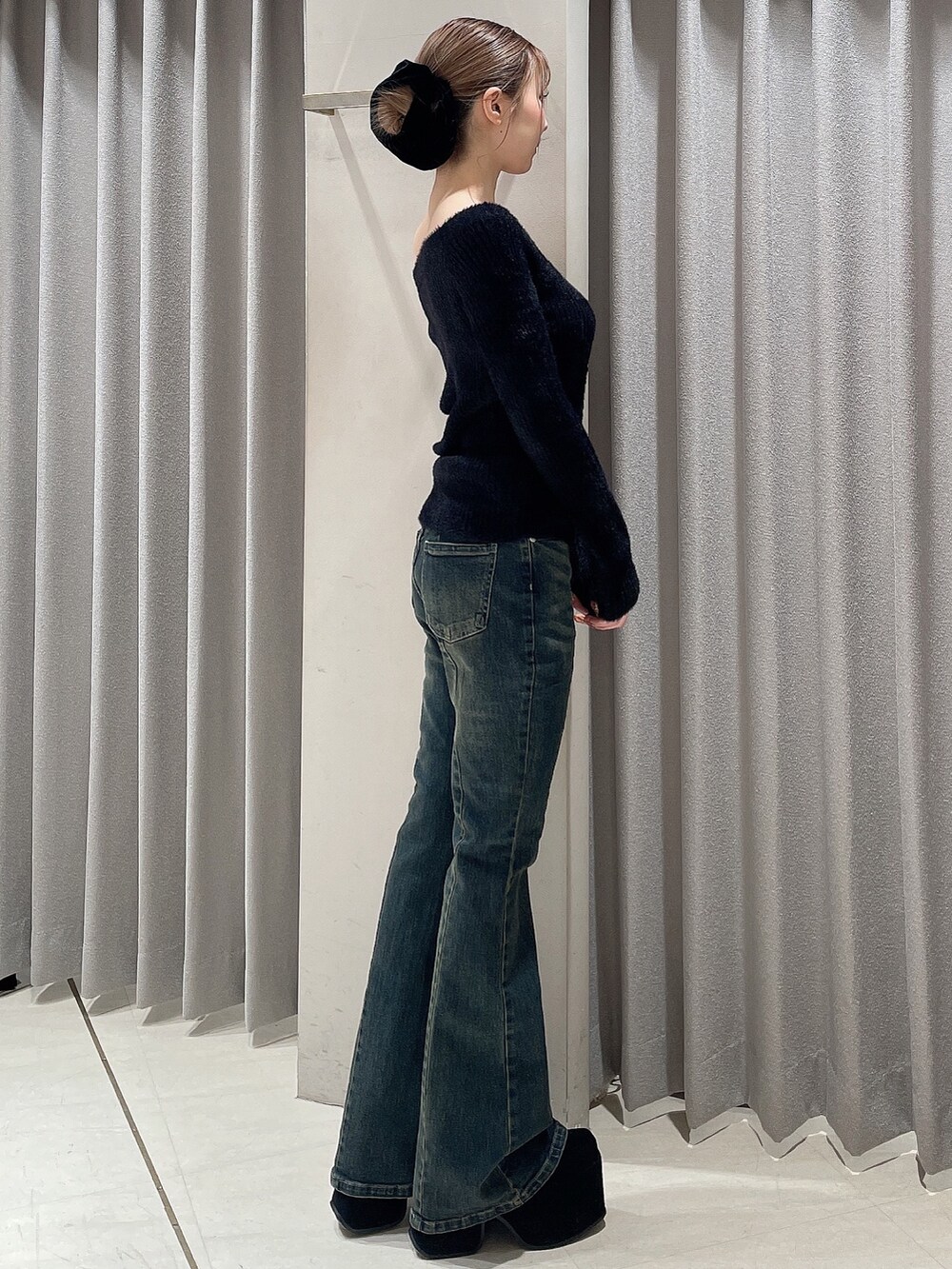 ブルー系のデニムパンツ、ブラック系のニット/セーター、ブラック系のブーツを着用したレディースの秋コーディネートの2枚目の写真