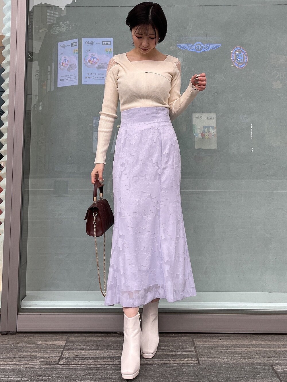 ホワイト系のブーツ、ブラウン系のハンドバッグ、ホワイト系のニット/セーターを着用したレディースの冬コーディネートの2枚目の写真