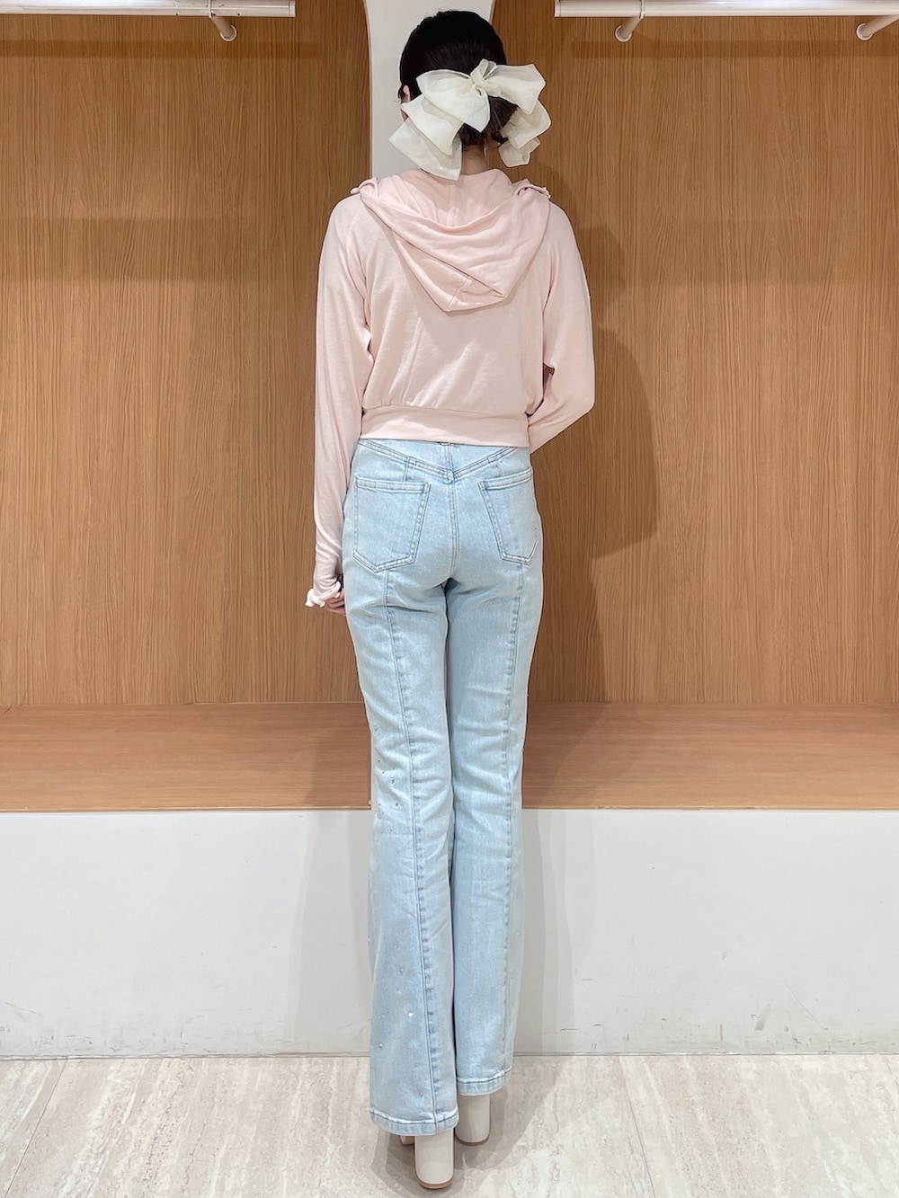 ピンク系のパーカー、ブルー系のデニムパンツ、ホワイト系のサンダルを着用したレディースの春コーディネートの3枚目の写真