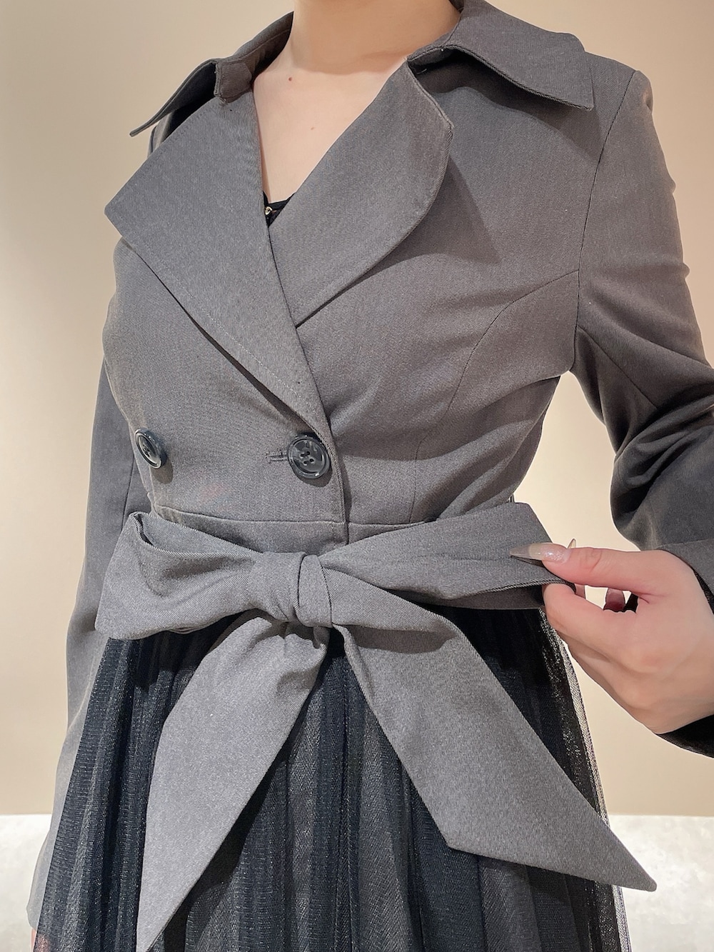 グレー系のトレンチコート、ブラック系のハンドバッグ、ブラック系のブーツを着用したレディースの秋コーディネートの8枚目の写真