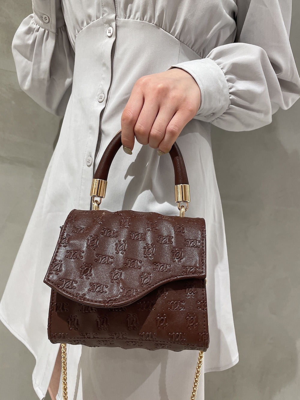 ブラウン系のハンドバッグ、ホワイト系のブーツ、グレー系のシャツワンピースを着用したレディースの冬コーディネートの6枚目の写真