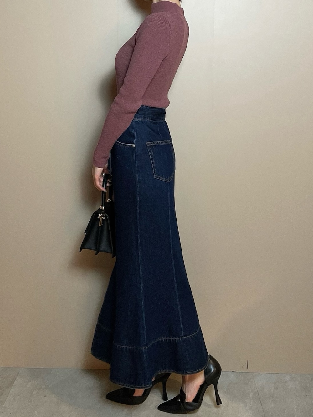 ピンク系のニット/セーター、ブルー系のデニムスカート、ブラック系のパンプスを着用したレディースの冬コーディネートの3枚目の写真