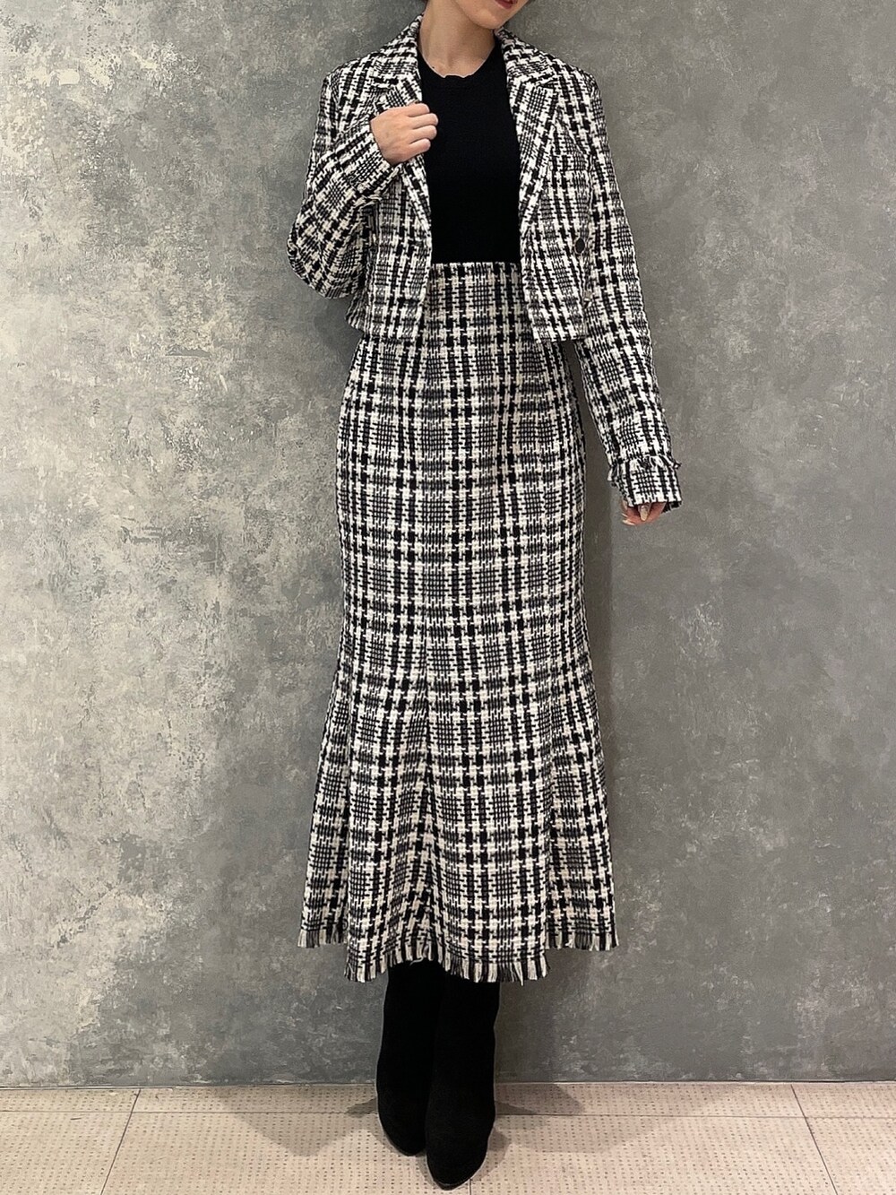 ブラック系のブーツ、ブラック系のスカート、ブラック系のテーラードジャケットを着用したレディースの夏コーディネートの2枚目の写真