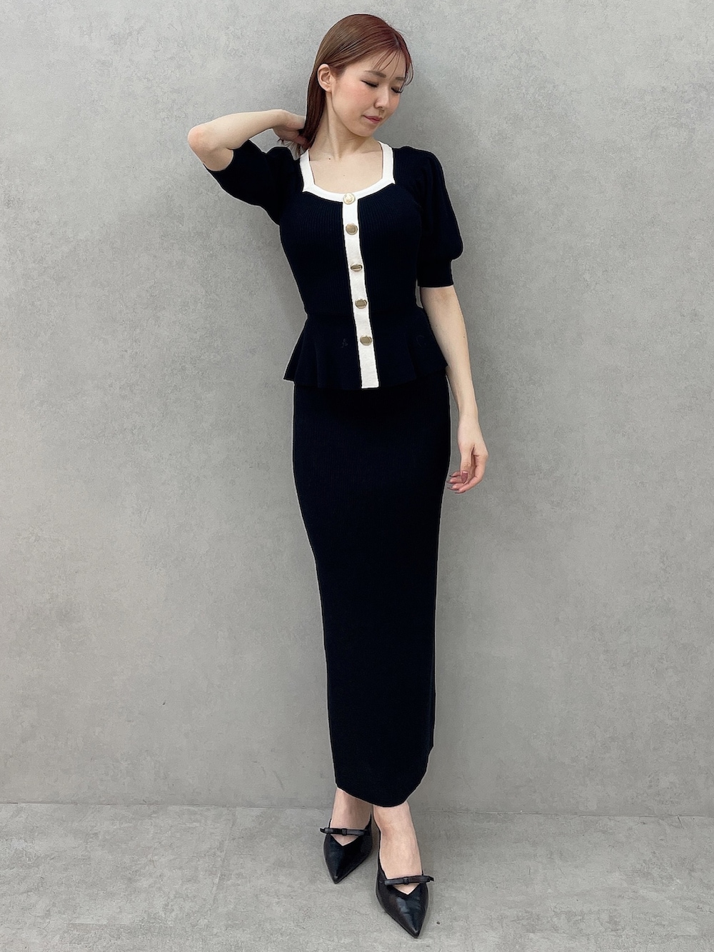 ブラック系のスカート、ブラック系のニット/セーター、ブラック系のパンプスを着用したレディースの冬コーディネートの2枚目の写真