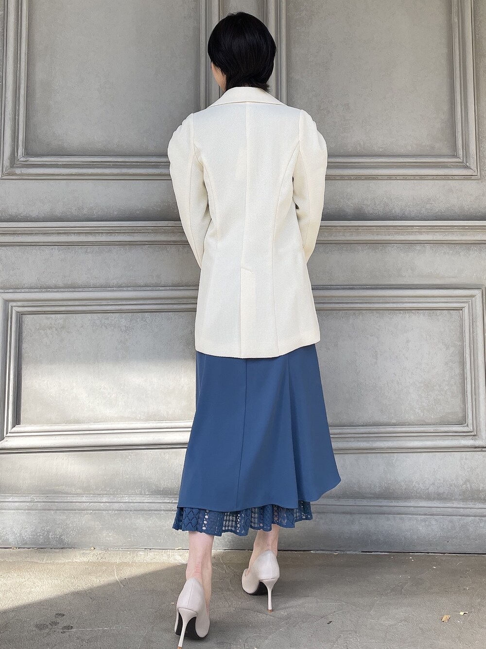 ホワイト系のテーラードジャケット、ブラウン系のハンドバッグ、ホワイト系のパンプスを着用したレディースの春コーディネートの3枚目の写真