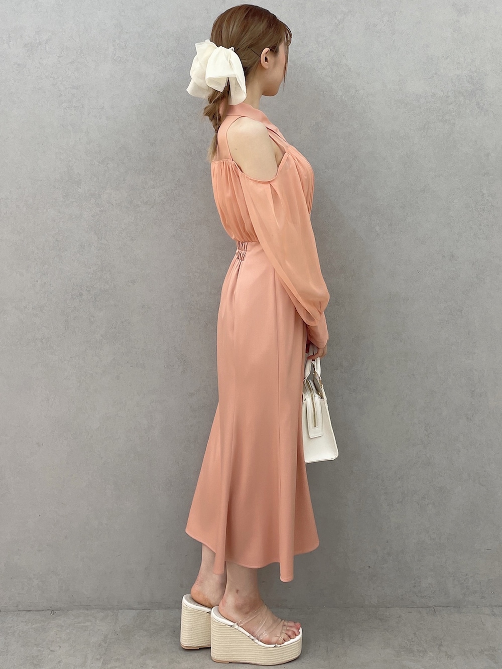 オレンジ系のワンピース、ホワイト系のハンドバッグ、ホワイト系のサンダルを着用したレディースの春コーディネートの3枚目の写真