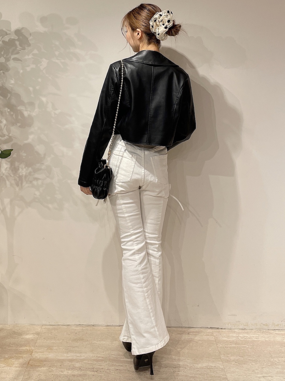 ブラック系のライダースジャケット、ホワイト系のデニムパンツ、ブラック系のブーツを着用したレディースの春コーディネートの4枚目の写真