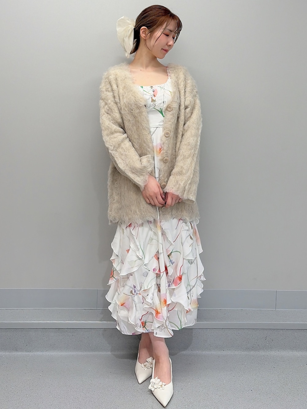 ベージュ系のカーディガン/ボレロ、ホワイト系のワンピース、ホワイト系のパンプスを着用したレディースの冬コーディネートの2枚目の写真