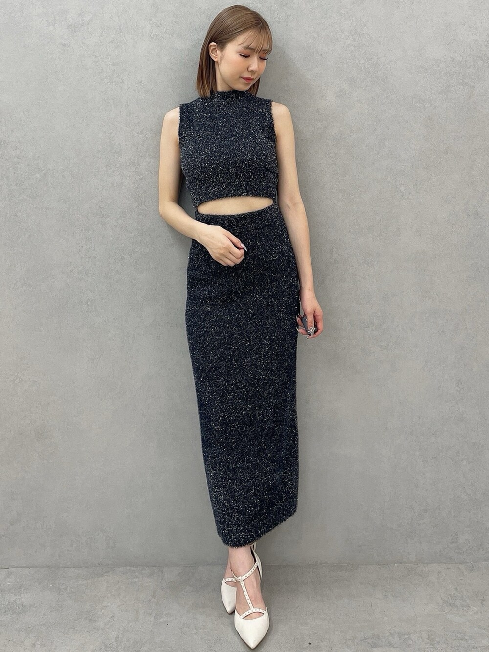 ブラック系のニット/セーター、ブラック系のスカート、ホワイト系のパンプスを着用したレディースの夏コーディネートの2枚目の写真