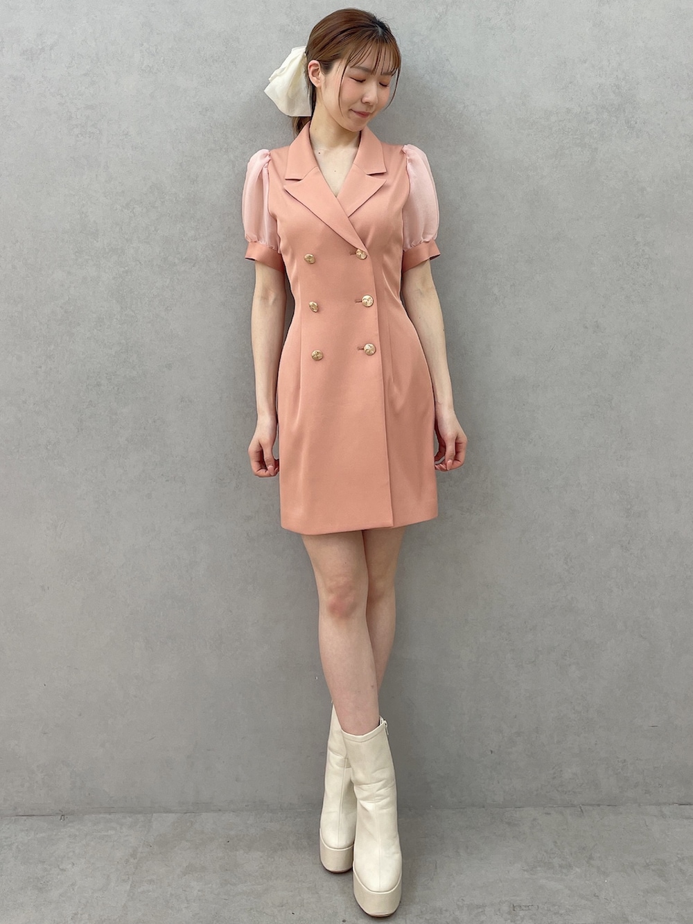 オレンジ系のワンピース、ホワイト系のブーツ、ホワイト系のバレッタ/ヘアクリップを着用したレディースの春コーディネートの2枚目の写真