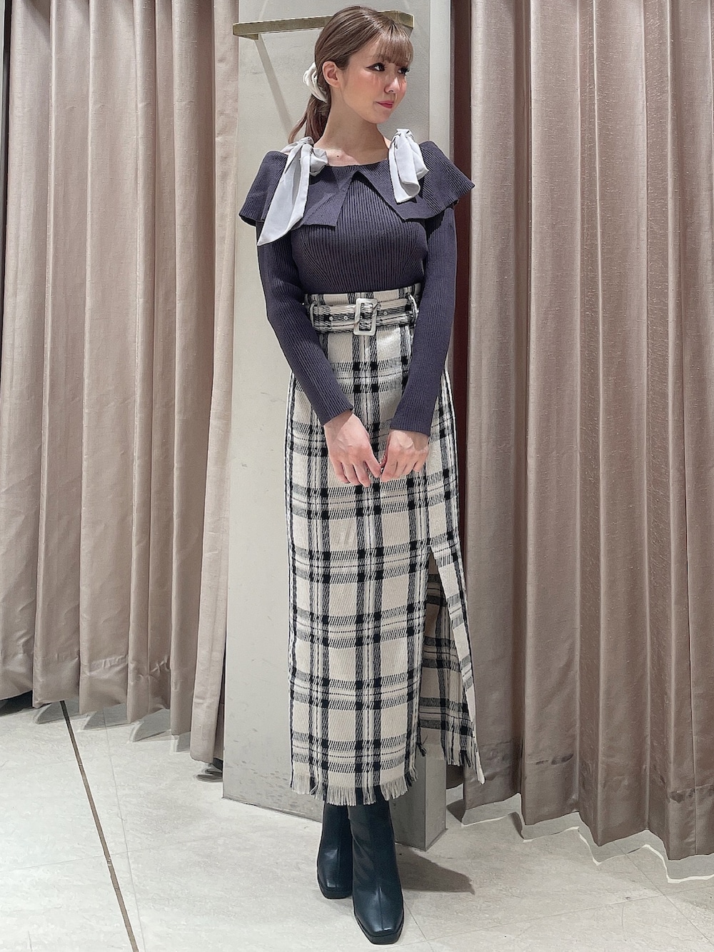 ブラック系のダウンジャケット/コート、グレー系のニット/セーター、ホワイト系のスカートを着用したレディースの秋コーディネートの5枚目の写真