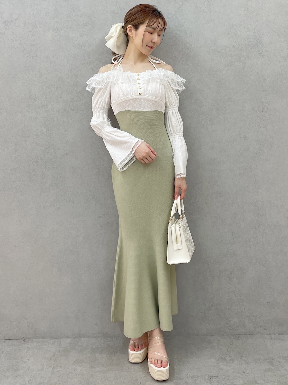 グリーン系のワンピース、ホワイト系のハンドバッグ、ホワイト系のサンダルを着用したレディースの春コーディネートの2枚目の写真