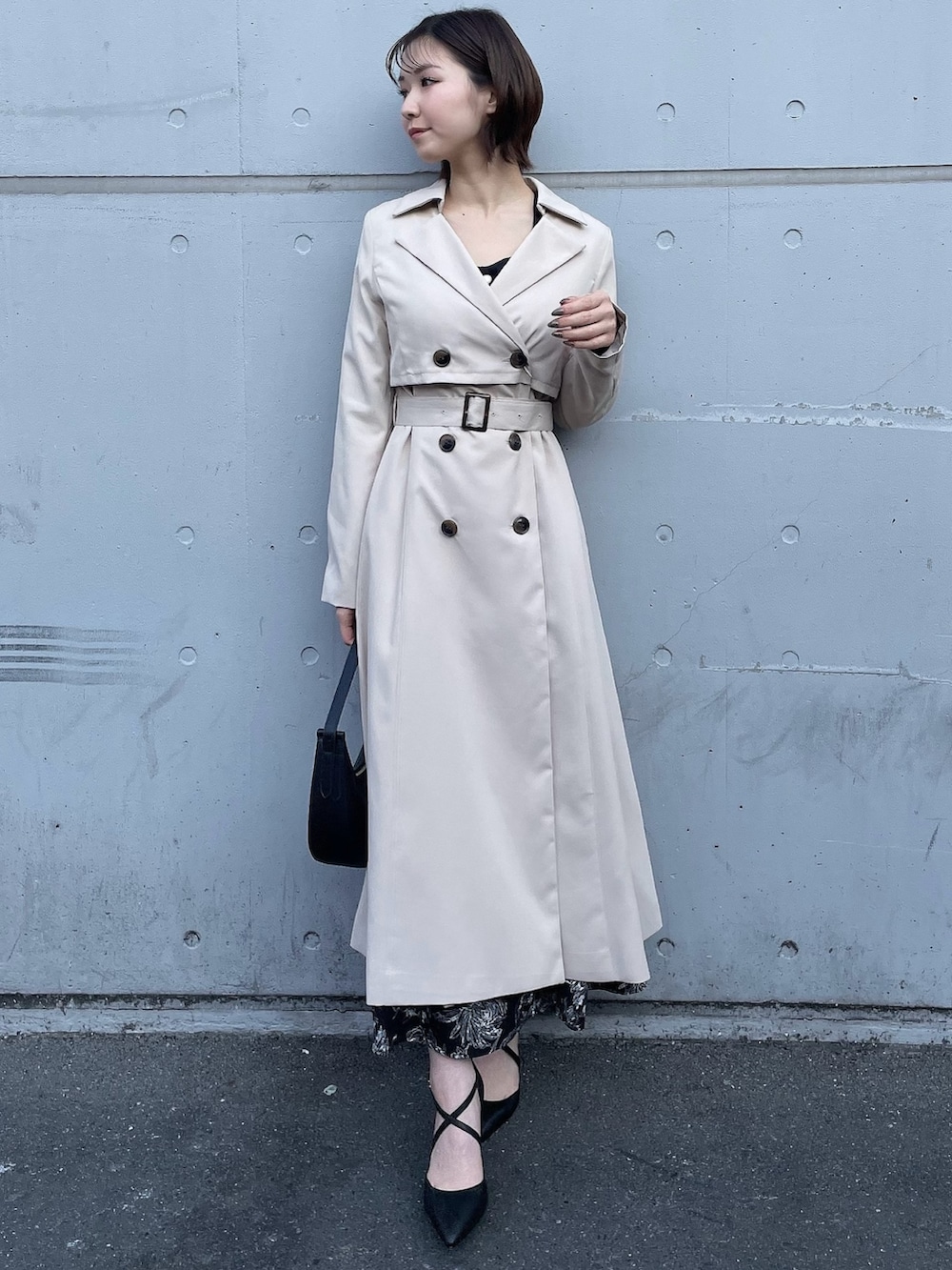 ベージュ系のトレンチコート、ブラック系のワンピース、ブラック系のハンドバッグを着用したレディースの冬コーディネートの4枚目の写真